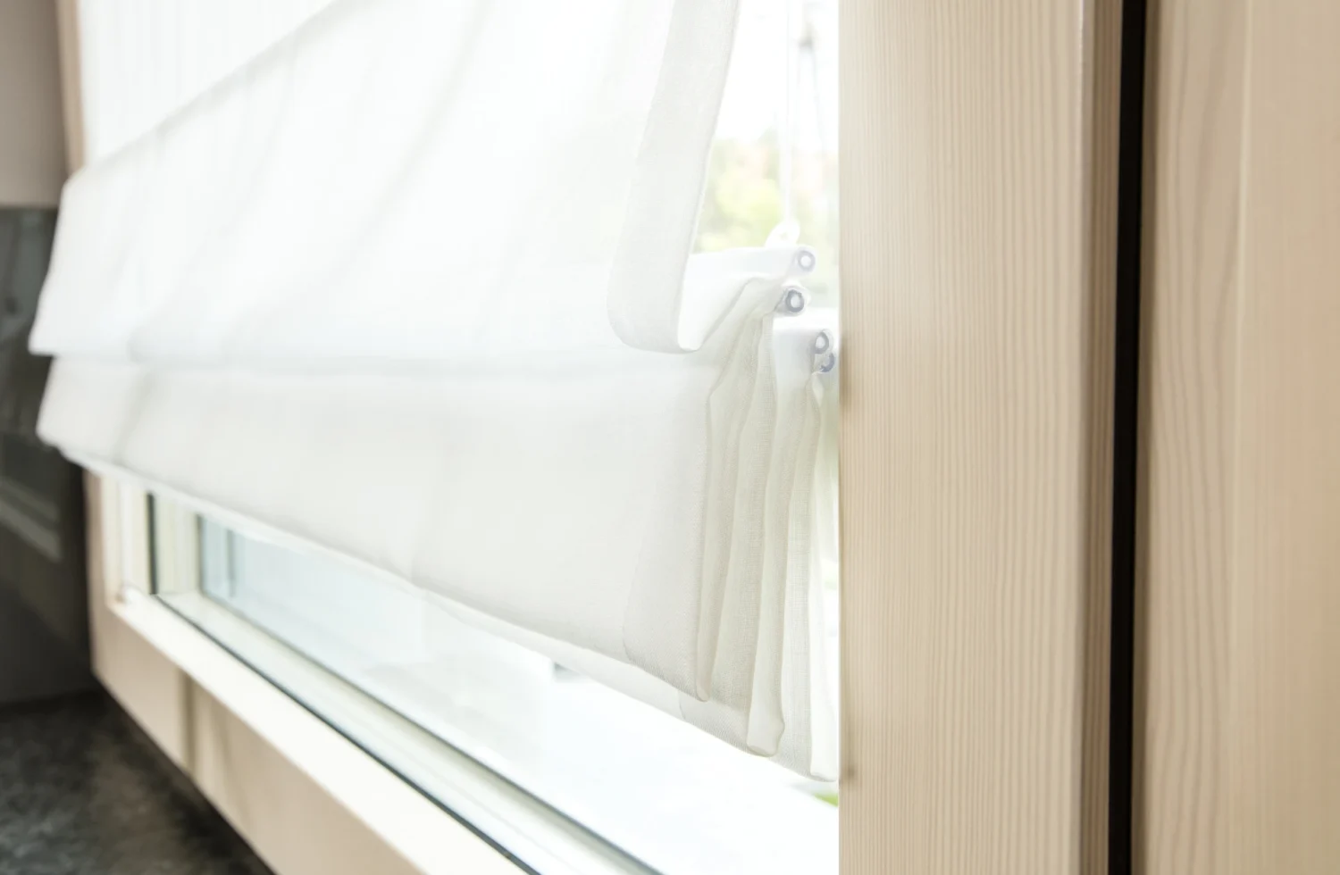 Nahaufnahme eines weißen Fensterrollos vor einem Holzrahmen