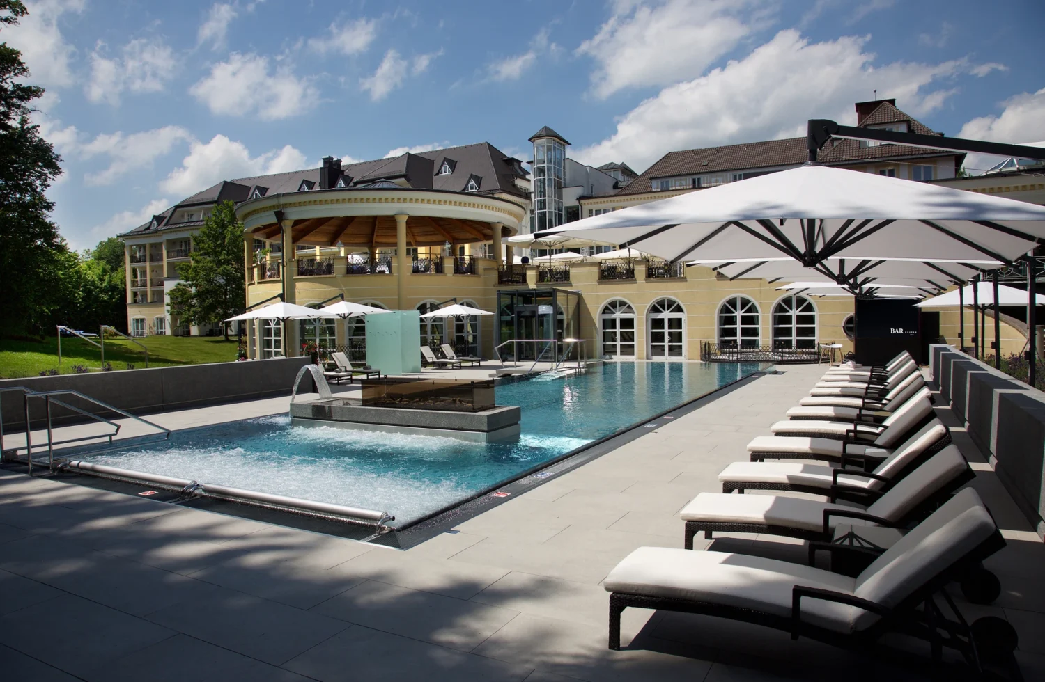 Luxuriöse Hotelanlage mit Außenpool und Liegestühlen bei sonnigem Wetter